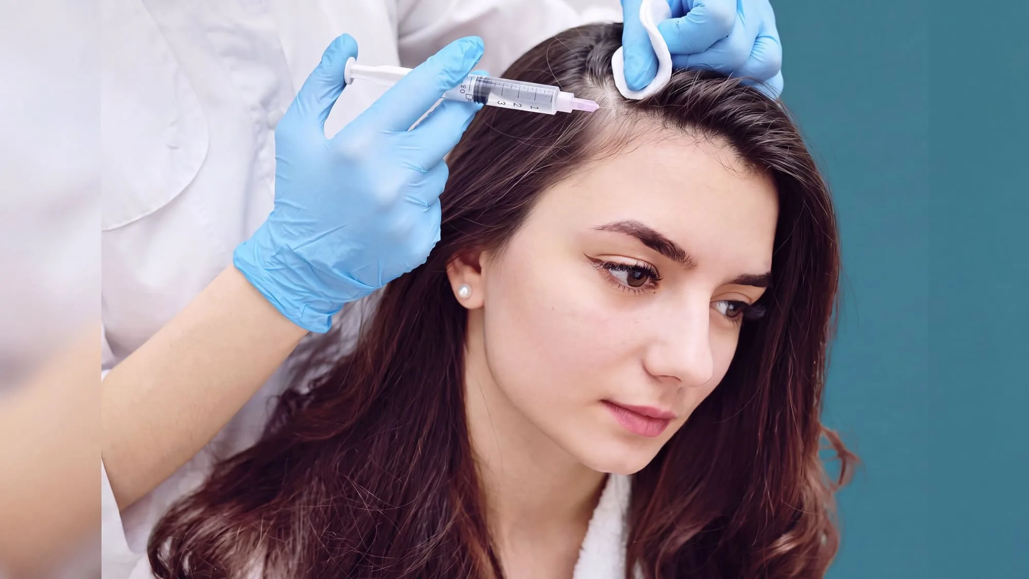 A seated patient receiving a fine injection along an exposed scalp part line during a hair restoration treatment