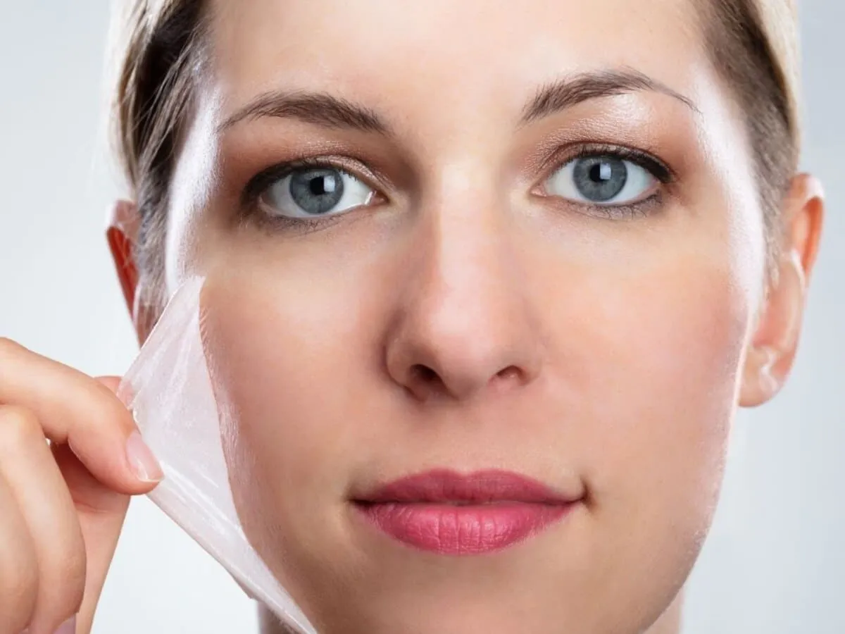 Woman lifting a translucent chemical peel film away from her cheek, revealing the resurfaced skin underneath
