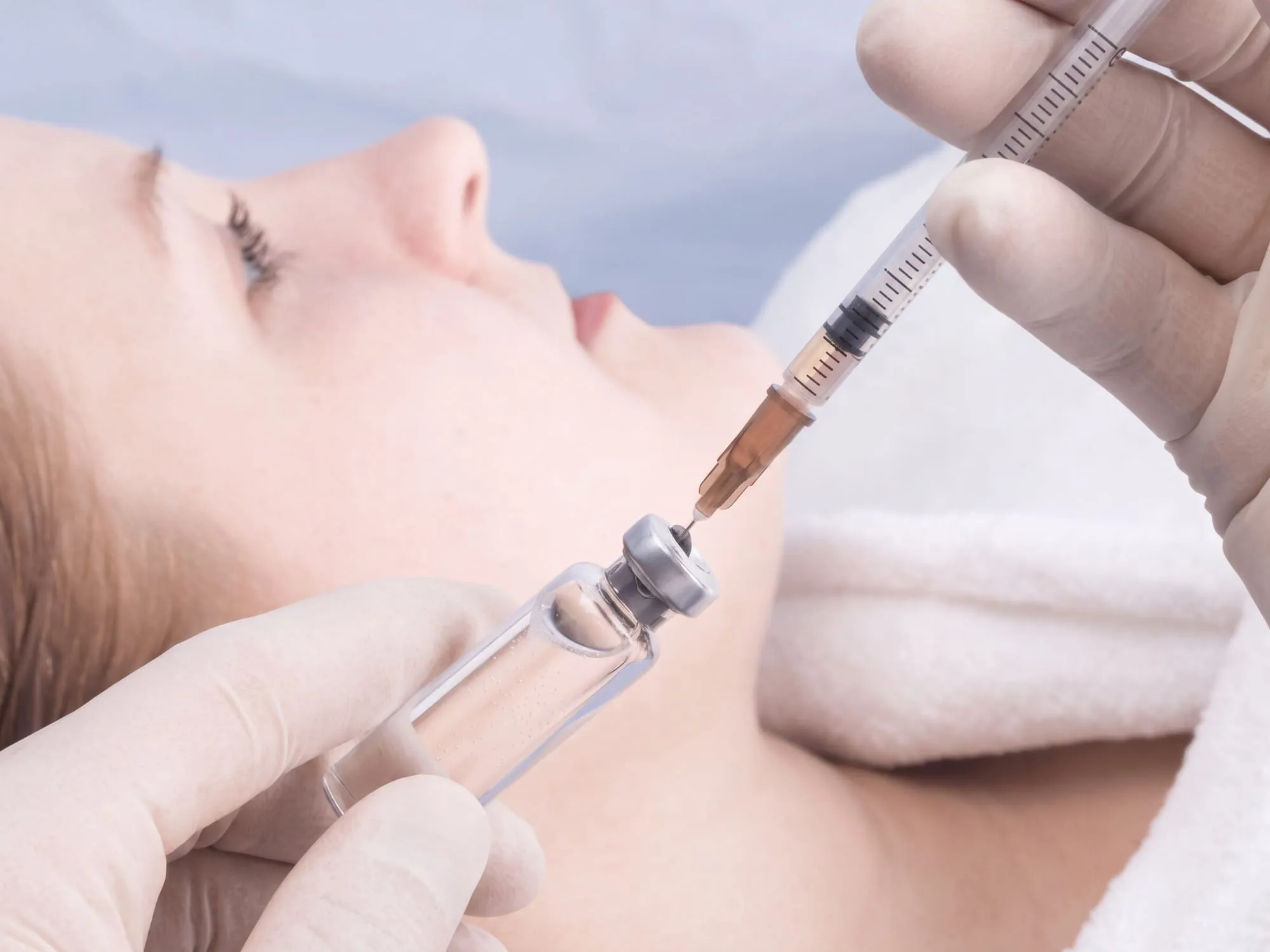 A gloved clinician drawing a prescription peptide from a small glass ampoule into a graduated syringe