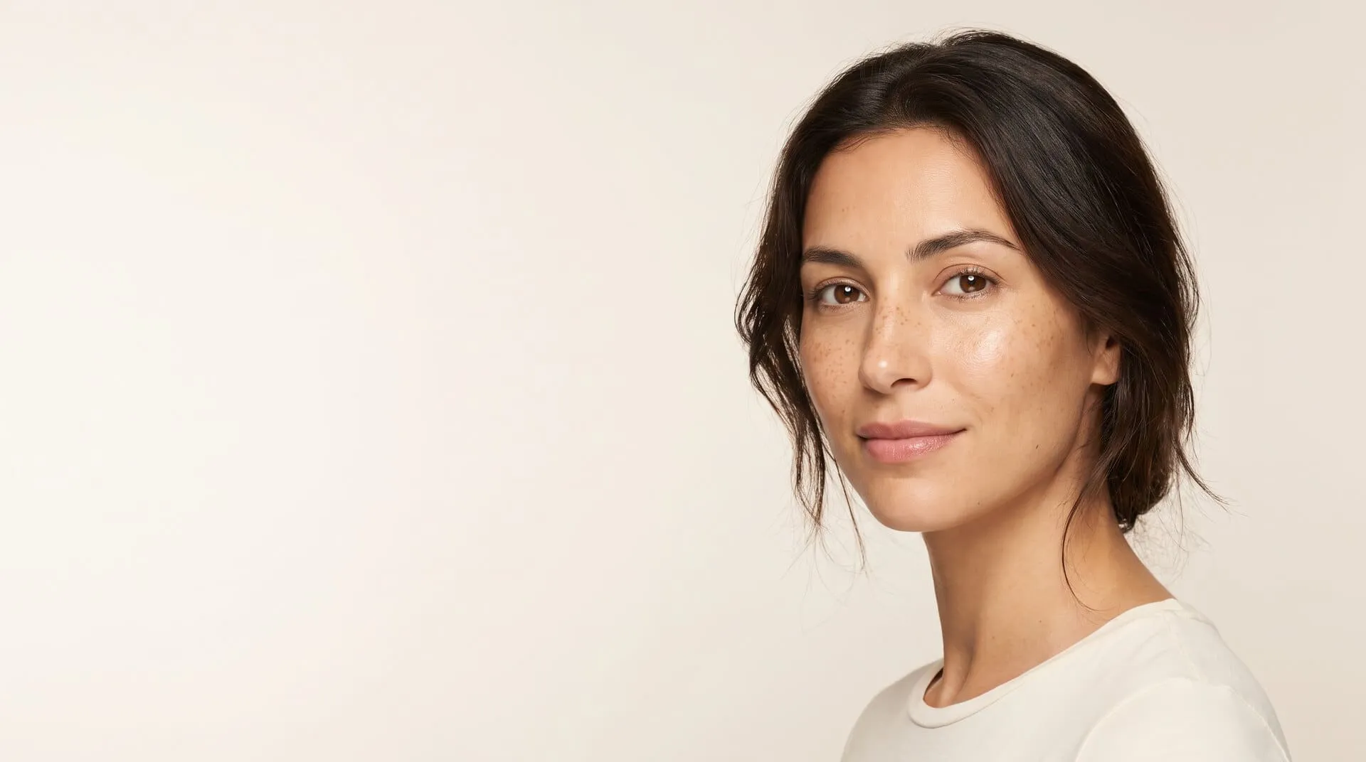 Studio portrait of a woman with sun freckling and sun spots across her cheekbones and the bridge of her nose, the pigment cumulative UV exposure leaves behind